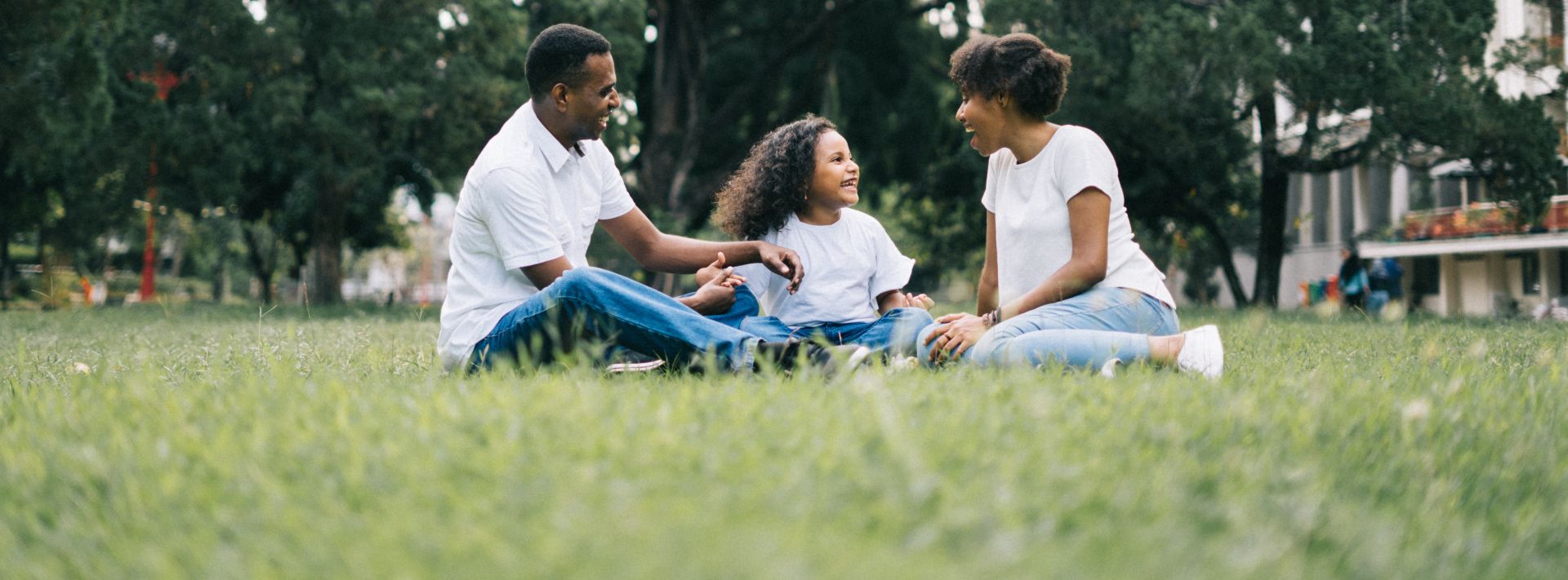 Family Sitting on Grass Near Building