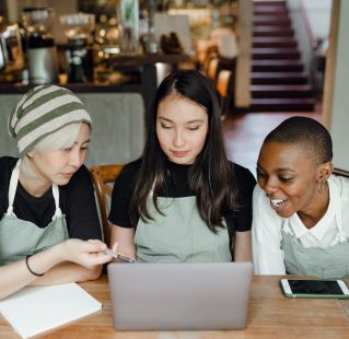 Happy waitresses watching tutorials on laptop